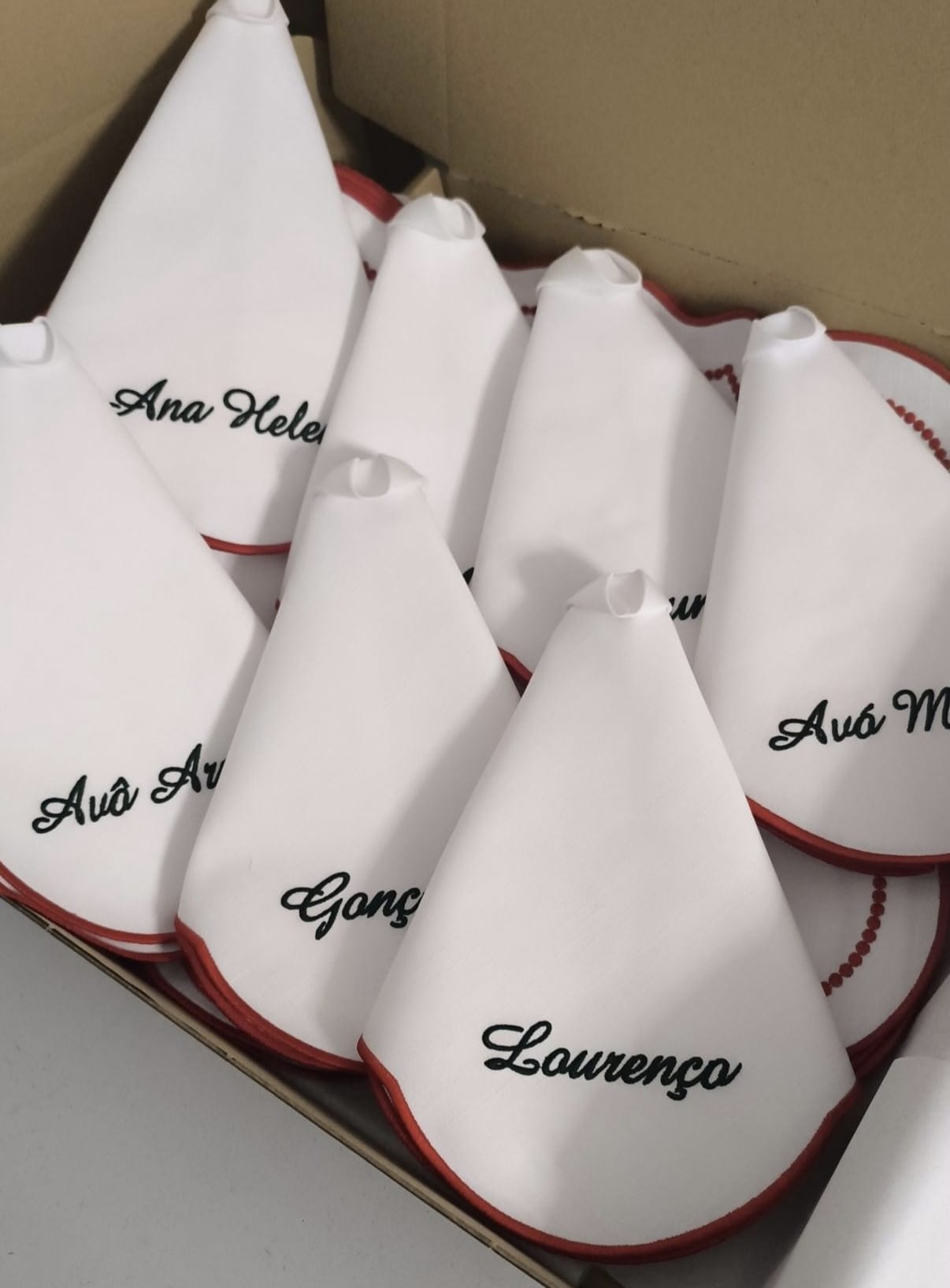 Conjunto de guardanapos brancos com nomes bordados e acabamento vermelho