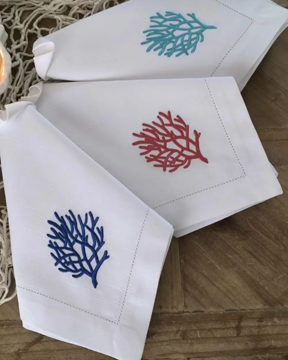 Guardanapos brancos com ponto aberto e bordados Corais em azul, vermelho e turquesa