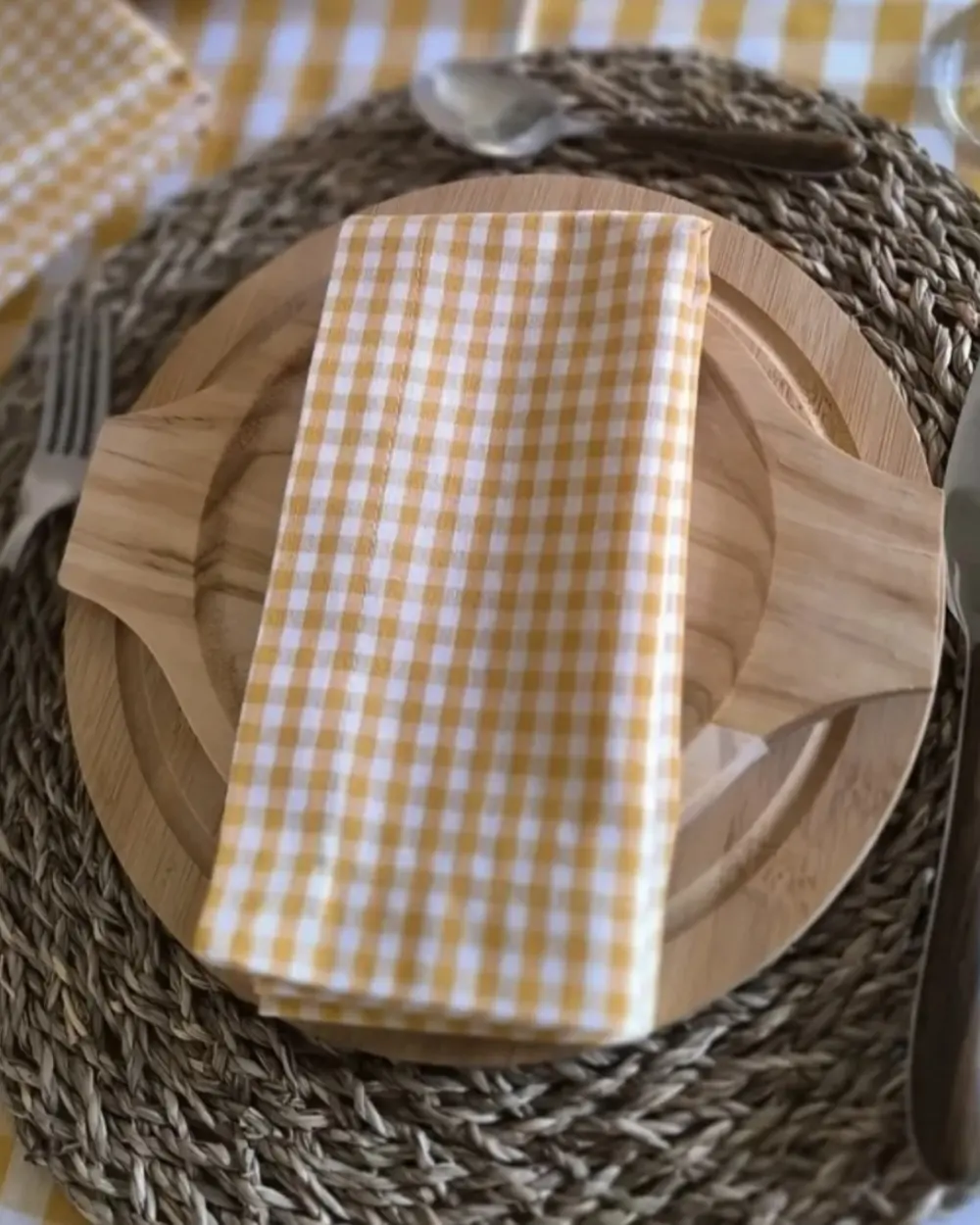 Guardanapo Vichy amarelo dobrado sobre prato de madeira