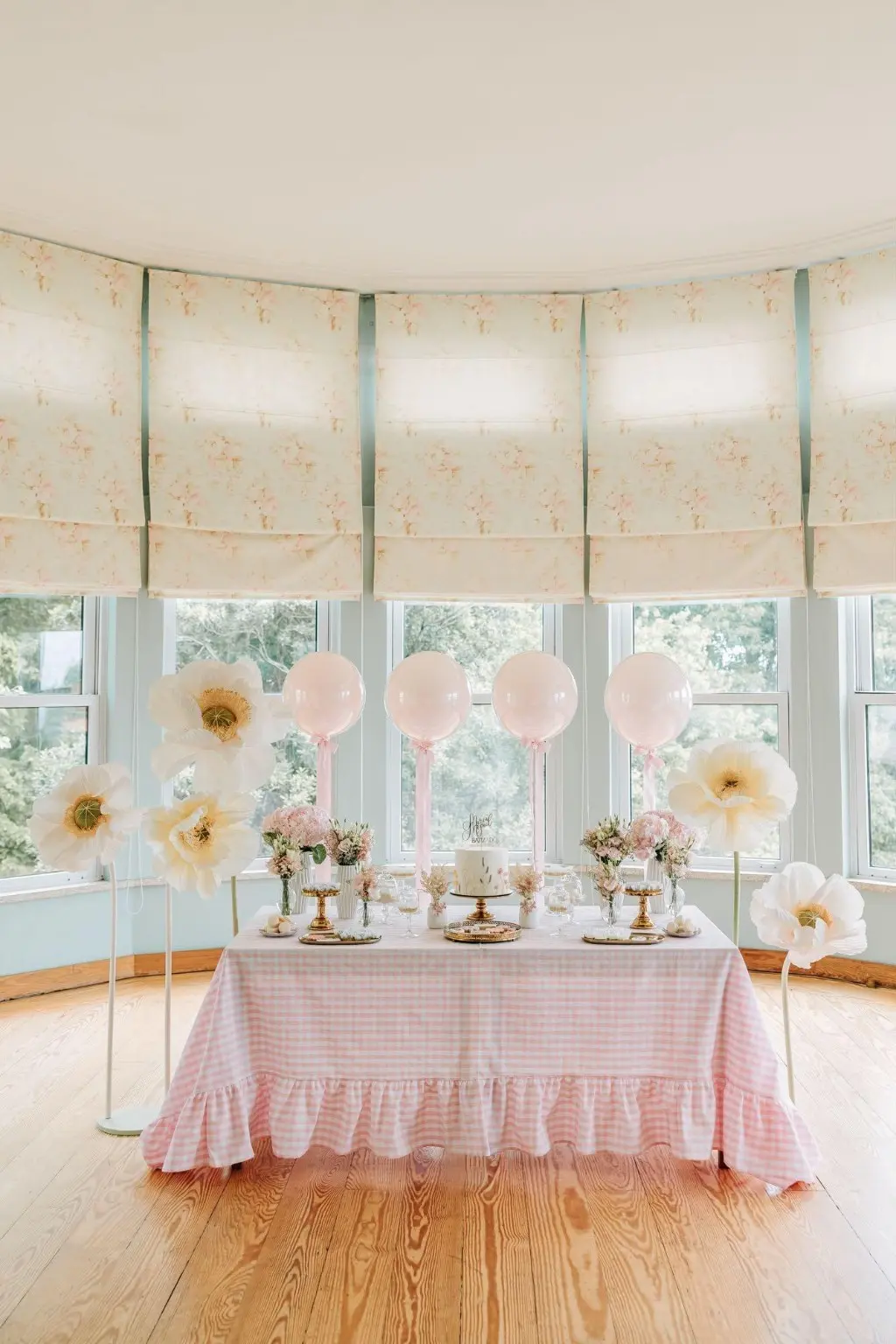 Mesa de festa infantil com toalha Vichy rosa com folho, balões e flores
