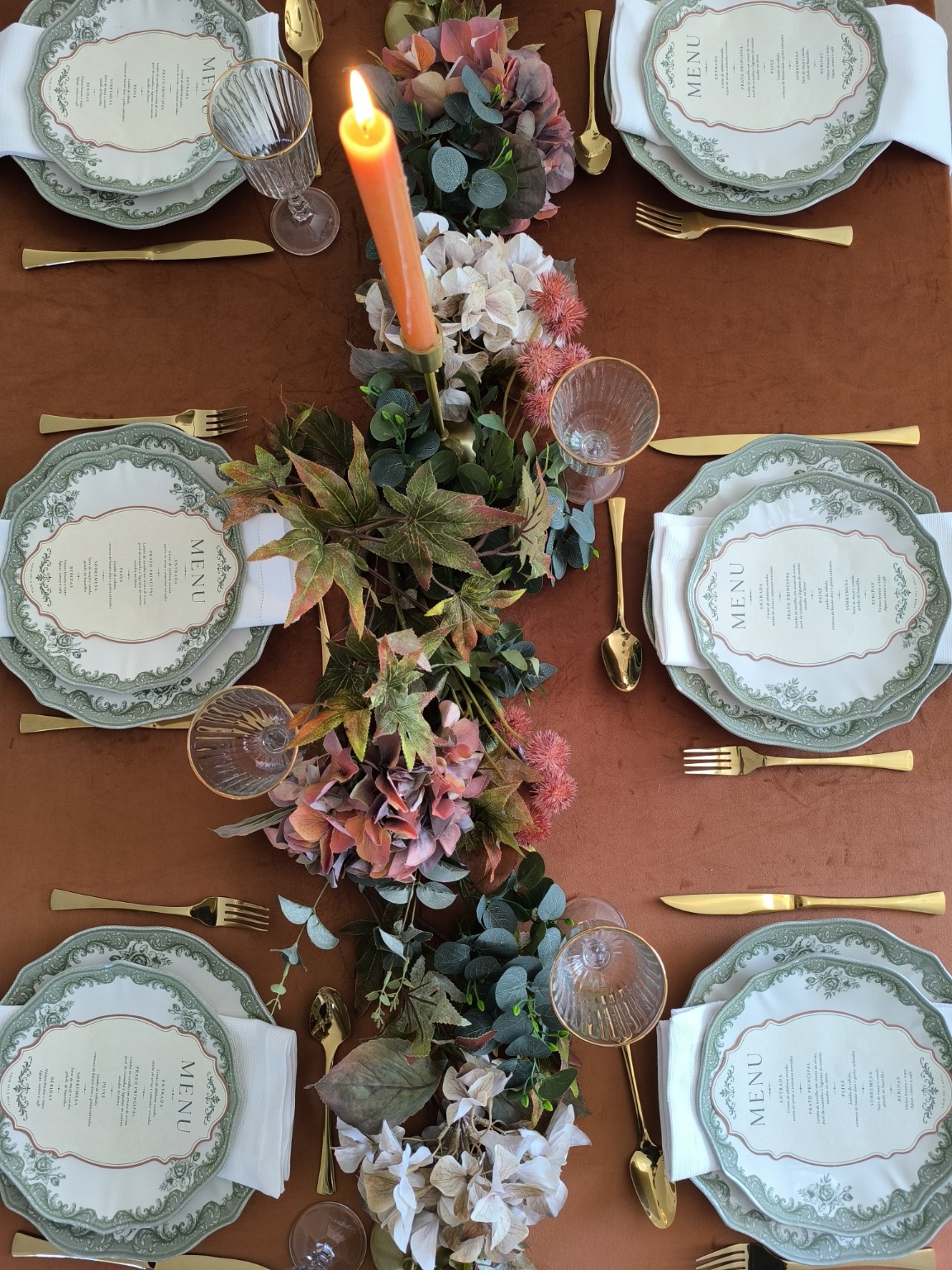 Mesa de evento em tons terracota vista de cima, com flores e loiça verde